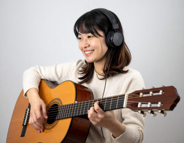 耳コピ練習中の笑顔の女性ギタリスト